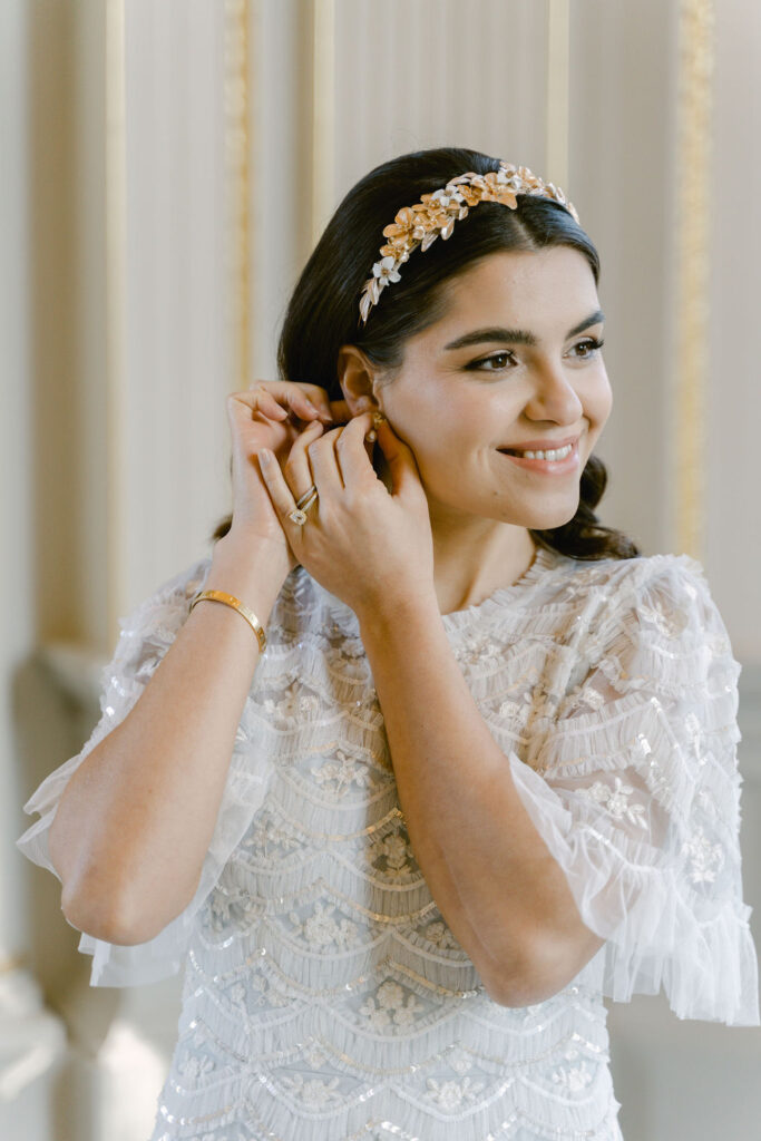 The bride wearing a sparkly blue fine art wedding gown, with a gold floral headband.