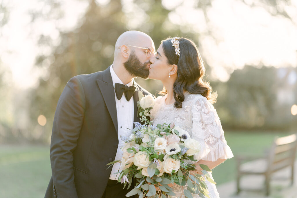 The bride and groom kiss in the golden light.