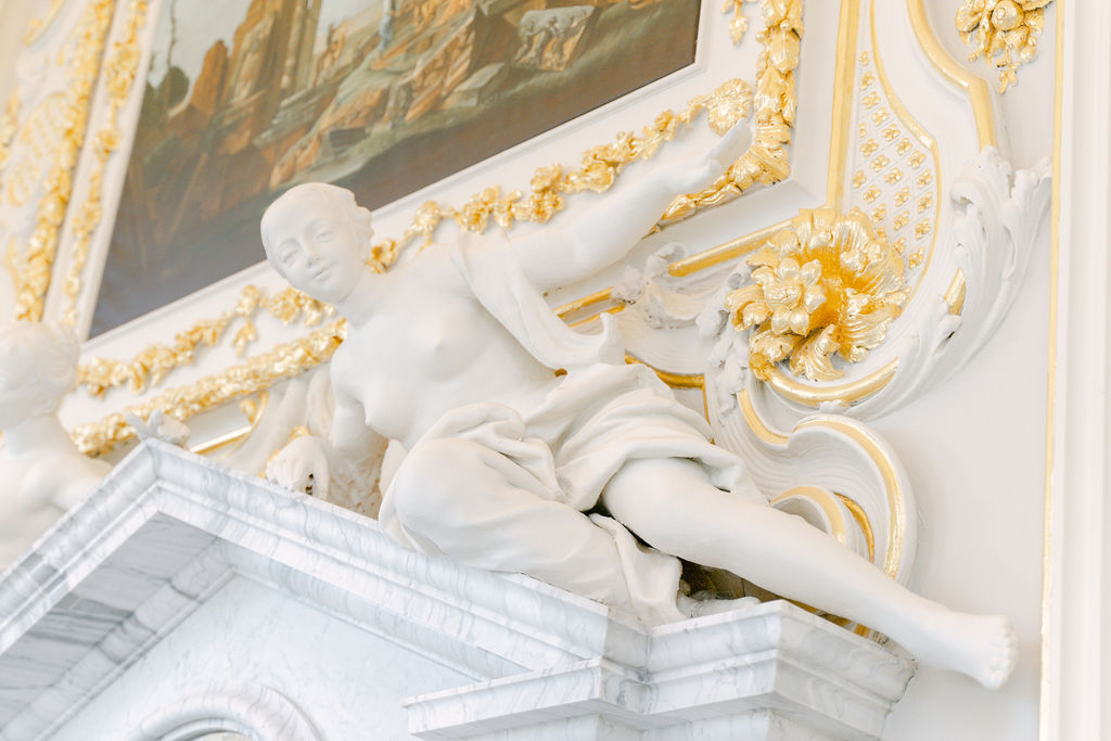 A close up of a fine art style stone putti cherub reclining on the mantlepiece of the Octagon Room.