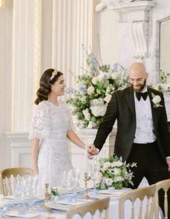 Bride and groom viewing their fine art style wedding reception table for the first time, in the Octagon Room at Orleans House Gallery. The room is Baroque in style and features a marble fireplace, black and white chequered floor and gold dining chairs.